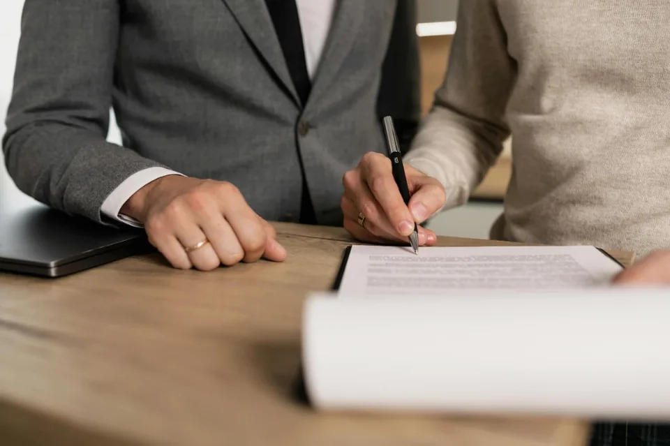 Professionals signing documents during a meeting at a desk