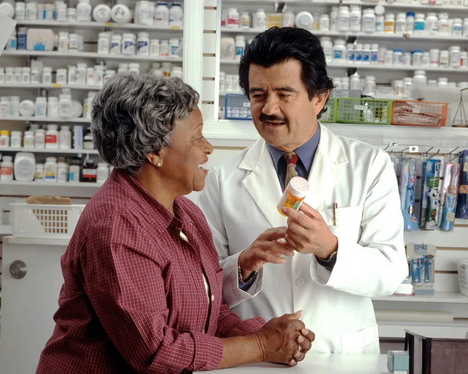 Pharmacist consulting with a senior customer at the pharmacy counter