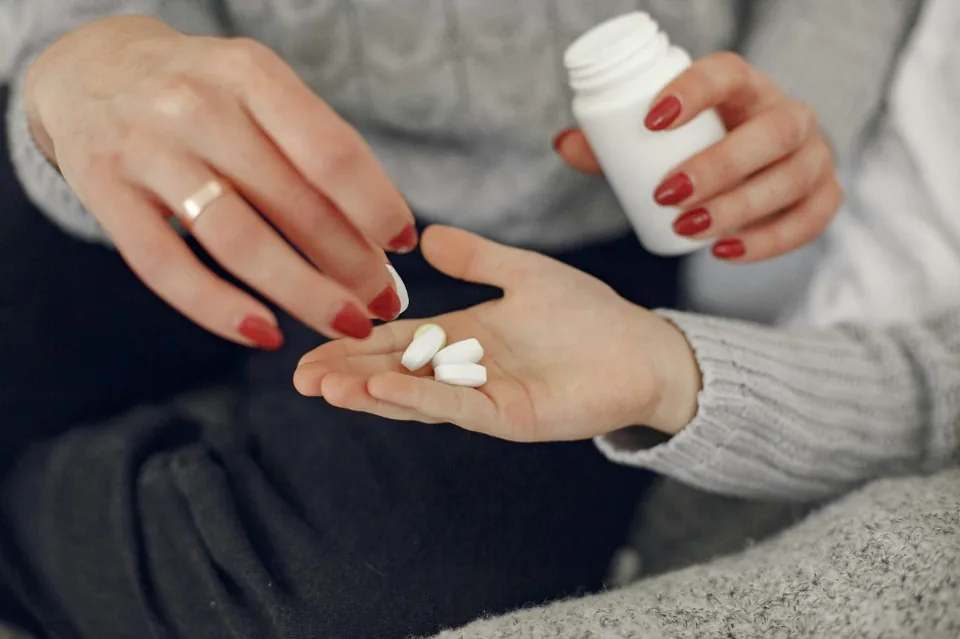 Pharmacist dispensing medication into a patient's hand from a prescription bottle